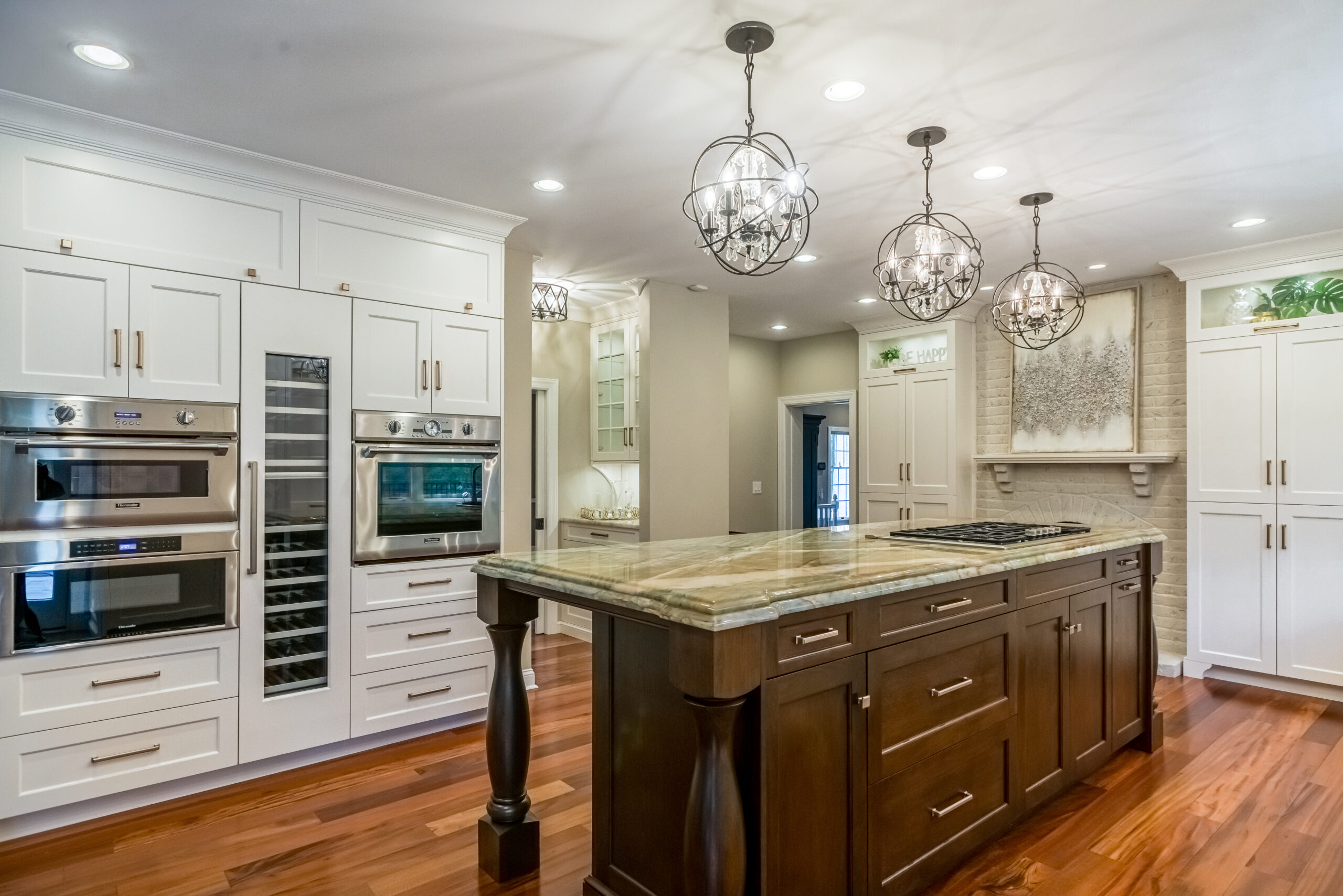 Kitchen: white cabinets, granite island, three orb chandeliers, built by Premier Custom Builders